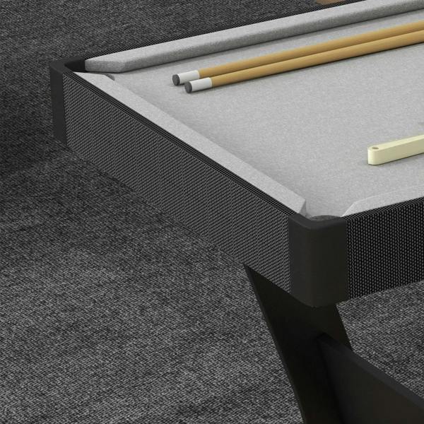 Grey pool table corner with black rail trim, textured bumper edge, and cue sticks on surface.