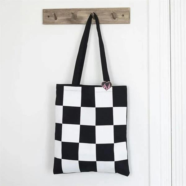 Black and white checkerboard tote bag with flaming heart enamel pin badge
