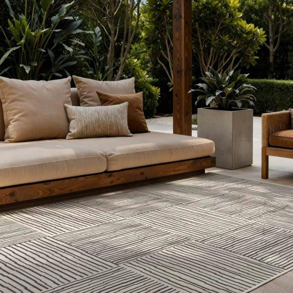 Outdoor patio with beige cushioned sofa, patterned rug, and potted plants.