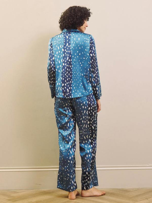 Woman wearing blue and white fawn patterned pyjamas against a beige wall.