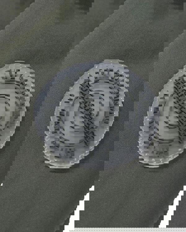 Lambretta Mens Utility Hooded Quilted Classic Badged Parka, close-up of the jacket's badge featuring embossed text and logo on olive green fabric.