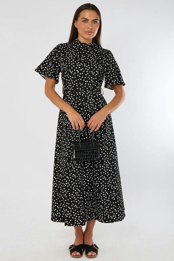 Woman wearing a black dress with white polka dots on a white background