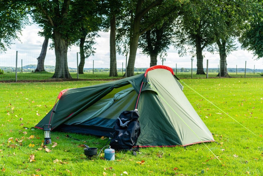 The Beckford Lightweight 2 Person Tent pitched on a camp with a backpack outside