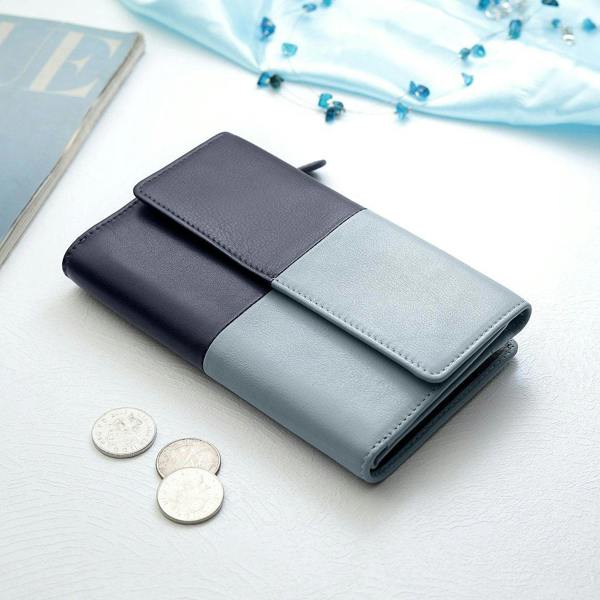 Clara Flapover Purse in navy and blue, closed and placed on a table, highlighting its modern and stylish appearance.