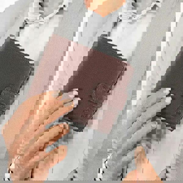 Person holding a brown leather wallet with a visible brand logo.