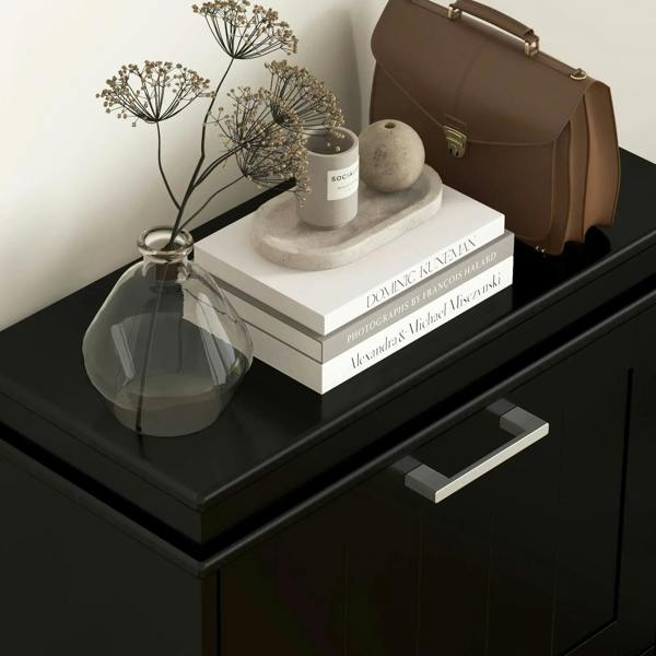Black shoe cabinet with top shelf and drawer pulls, styled with decor items