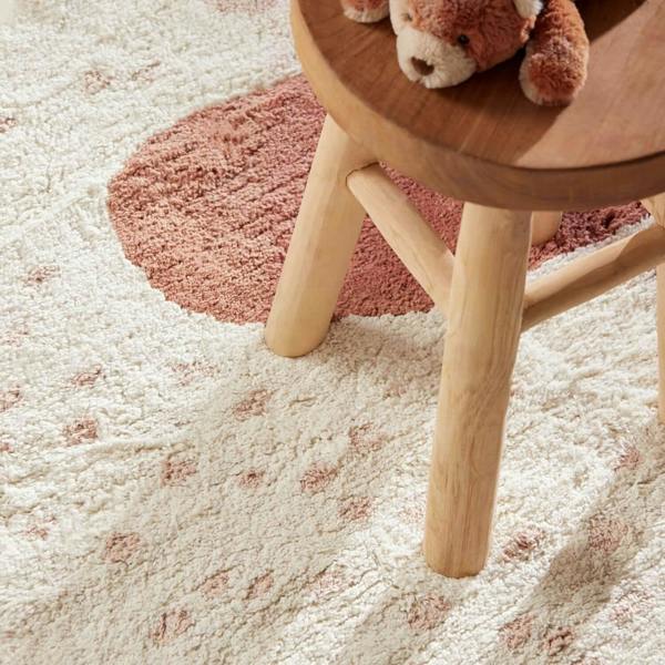 Wooden stool with a teddy bear on a textured pink and white rug