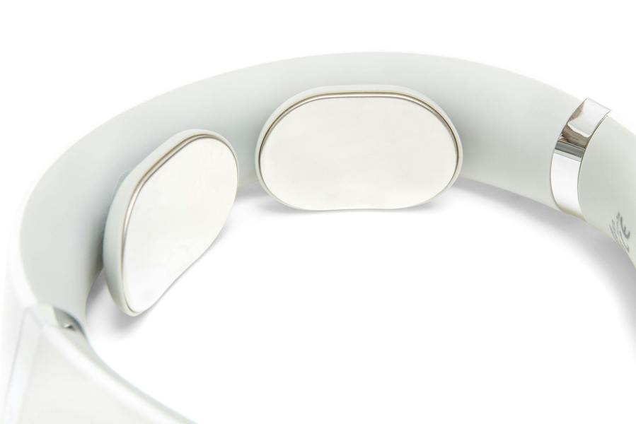 Close-up of the Neck & Shoulder Massager, showing its white design with two smooth, oval metal pads inside for skin contact and electrical muscle stimulation.