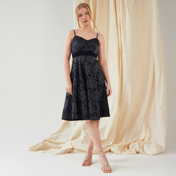 The model is wearing a Sarvin Jacquard Fit And Flare Dress with black lace.