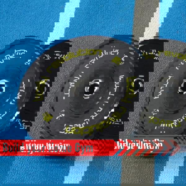 Black Olympic bumper plates with bright yellow lettering, showcasing 15 kg weight, ideal for home gym setups on a blue mat