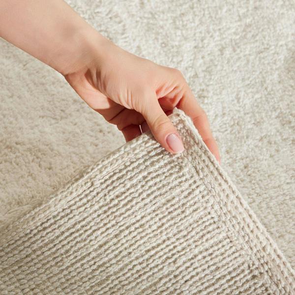 Hand holding a textured beige fabric against a matching background