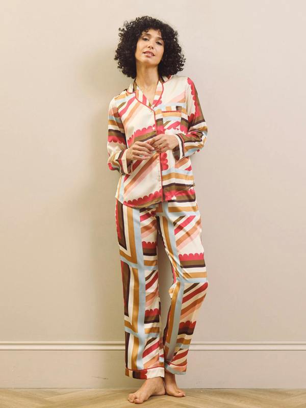 Woman wearing a colourful striped pyjama set against a plain background