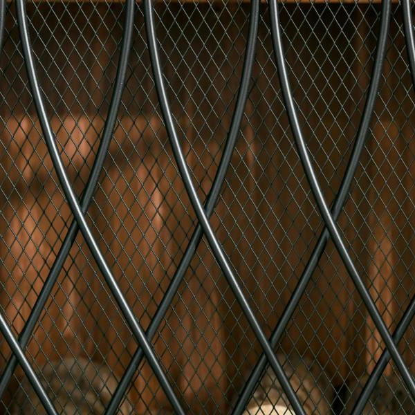 Closeup of black metal mesh panel with diamond grid and vertical bars