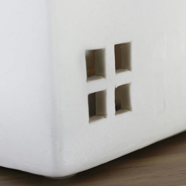 A close-up detail shot showing the intricate square cut-out windows of the unlit white ceramic Christmas LED house.