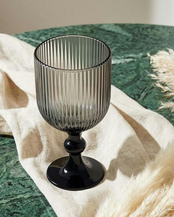 Smoky grey glass goblet on a wooden surface with blurred background