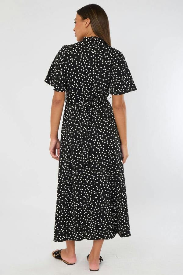 Woman wearing a black dress with white polka dots on a white background
