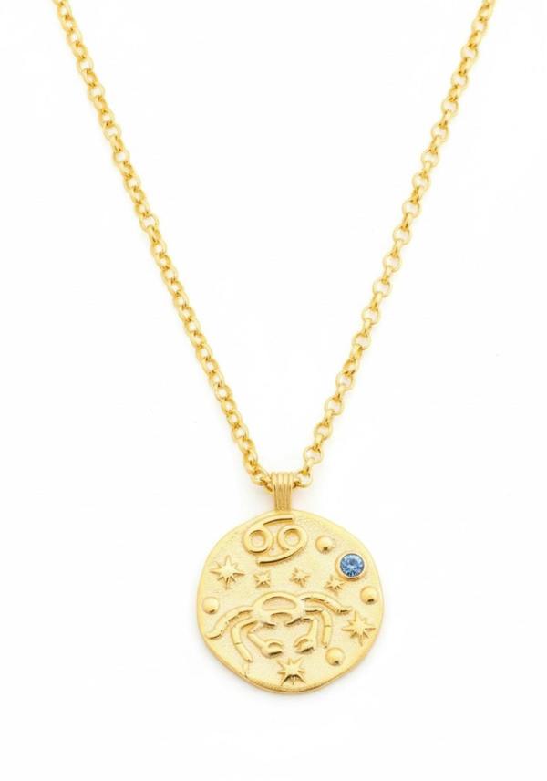 Gold necklace with a round pendant featuring astrological symbols on a white background