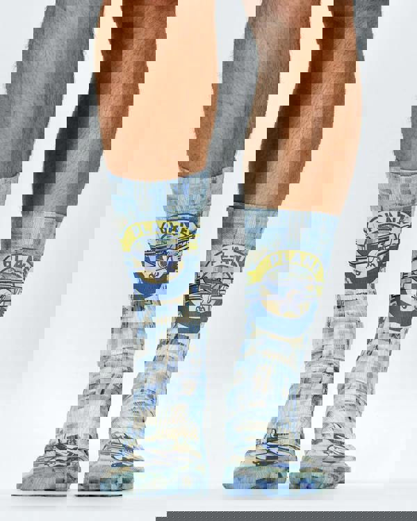 Blue and yellow checkered socks with airplane design worn by a person on a white background