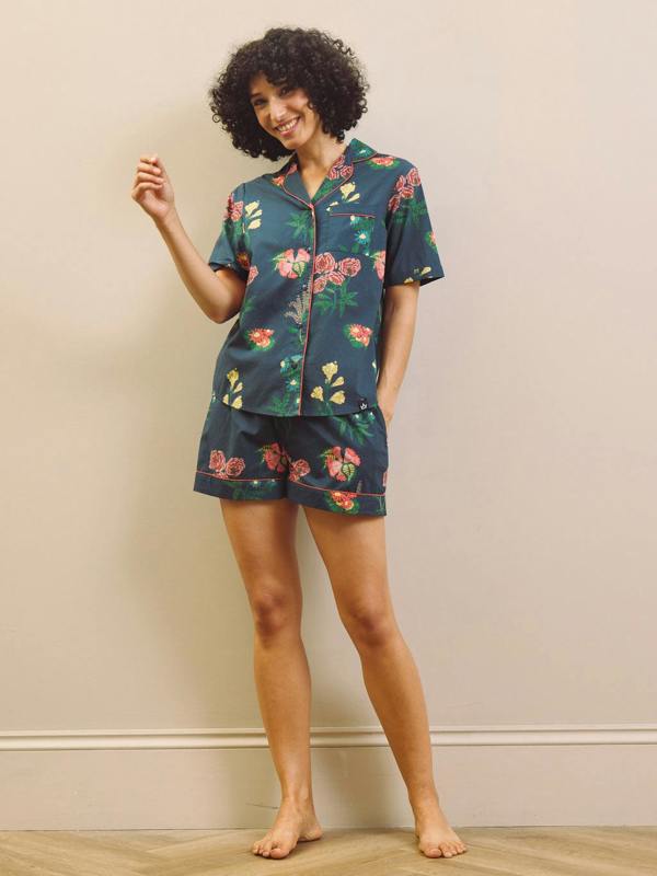 Woman wearing a navy floral short pyjama set against a plain background
