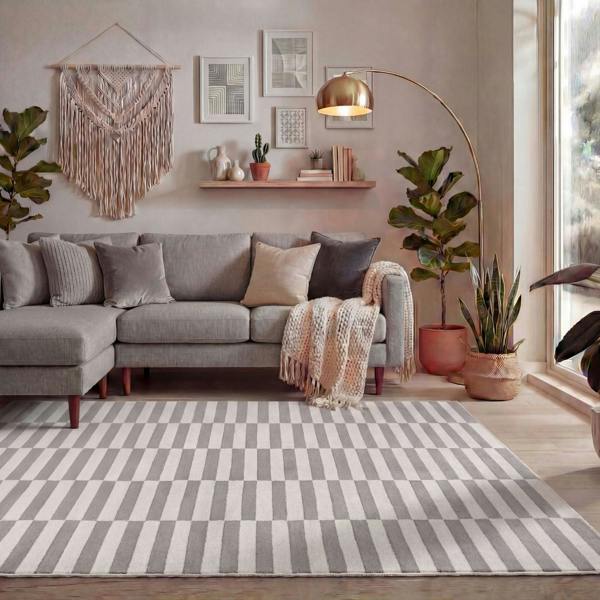 Living room with a gray sectional sofa, striped rug, and decorative elements.