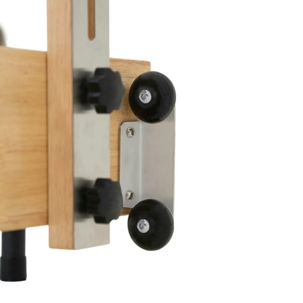 Close-up of the Pilates reformer machine's oak frame with black rubber wheels and metal components for smooth movement and stability