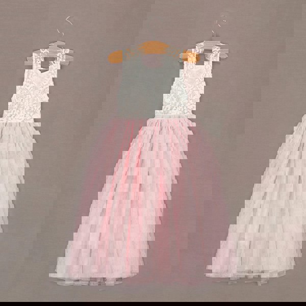 Pink and white dress on a hanger against a brown background