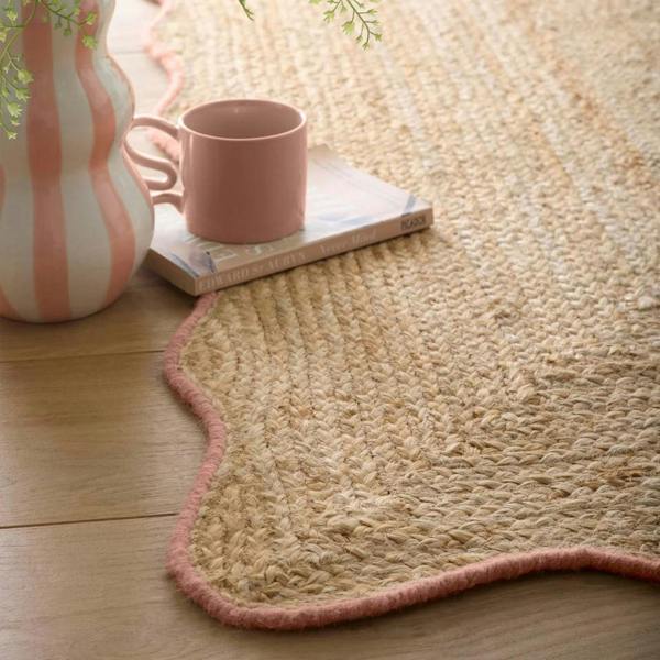 Natural fiber rug with a pink mug and striped vase on a wooden floor