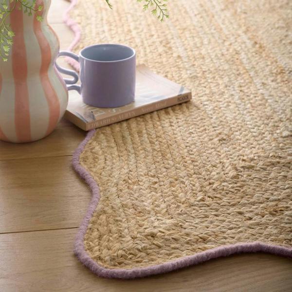 Beige woven rug with a purple mug and striped vase on a wooden floor