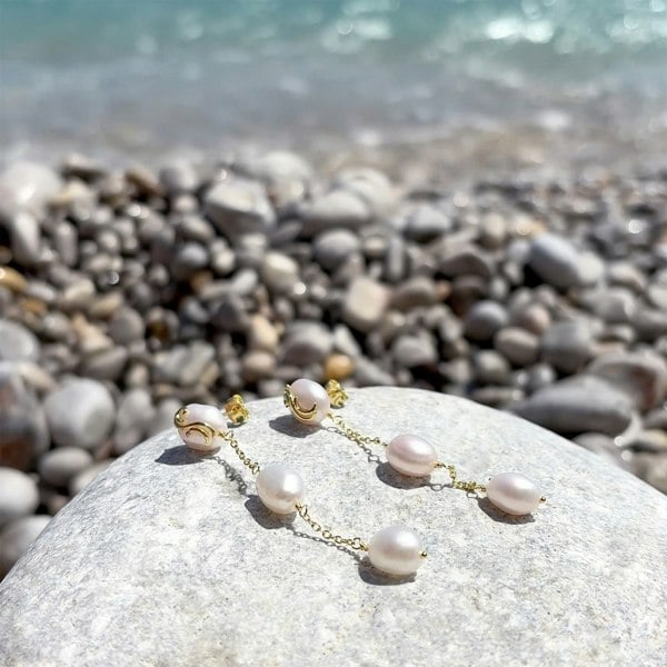 Elegant pearl drop earrings with a beachside backdrop.