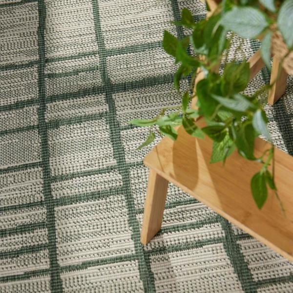 Wooden plant stand with a plant on a green and white checkered rug
