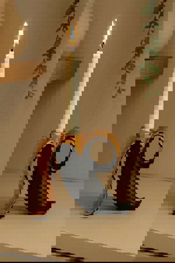 Decorative candle holder with a lit candle on a neutral background