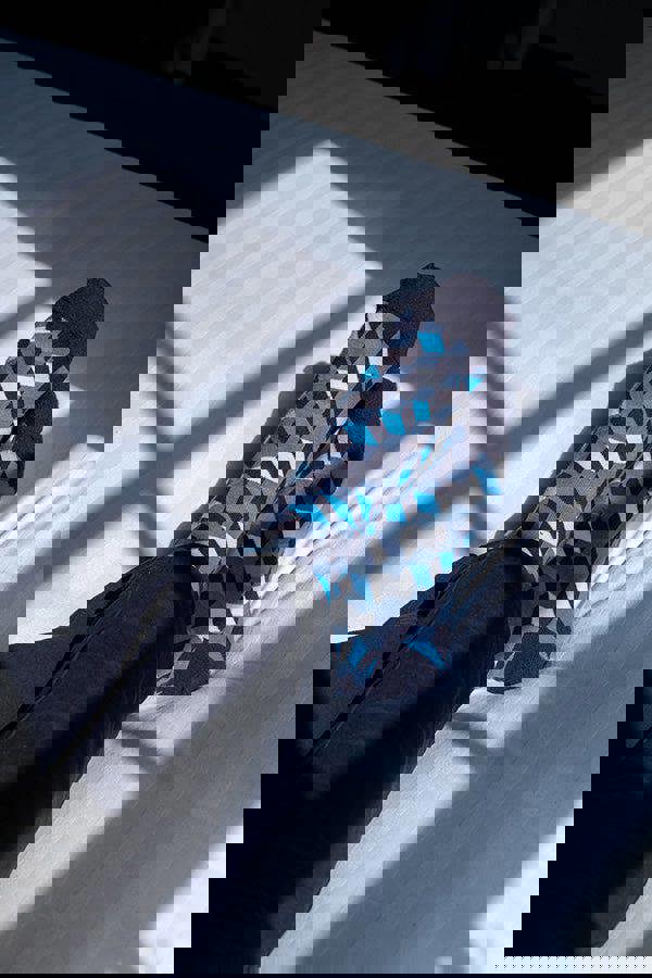 Person wearing patterned socks on a light-colored floor with shadows cast by a window.