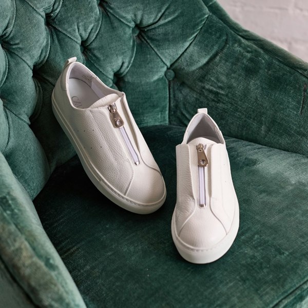 estella white trainers on green chair
