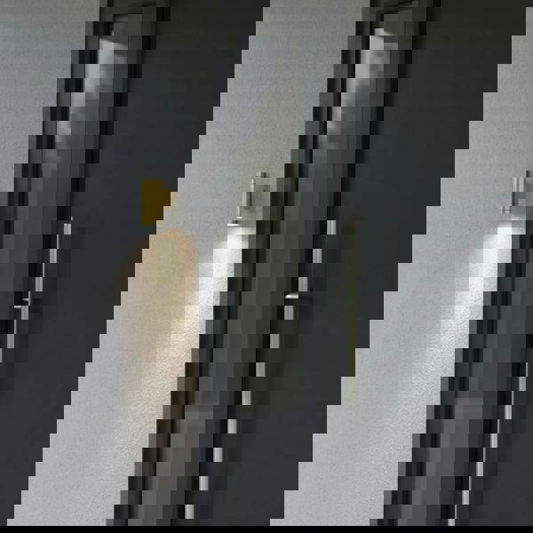 exterior brass wall light mounted on awhite textured wall outside the front door of a modern home 