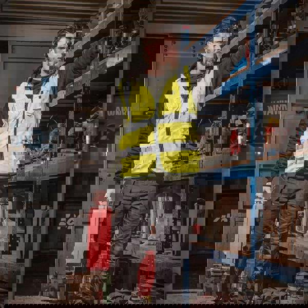 Scruffs High Visibility Mens Hi-Viz Technical Zip Up Vest, a man in high visibility yellow vest with reflective strips working in a workshop.