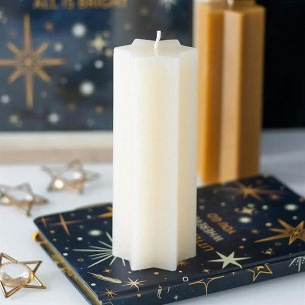 Cream taper candle with star-shaped top and unlit wick on straight body