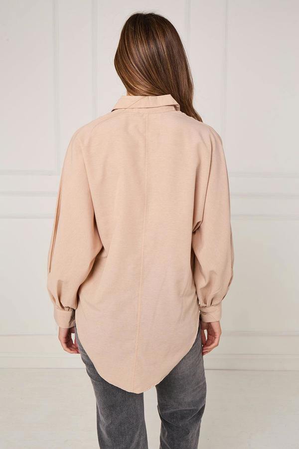 Person wearing a beige shirt and gray pants against a white background