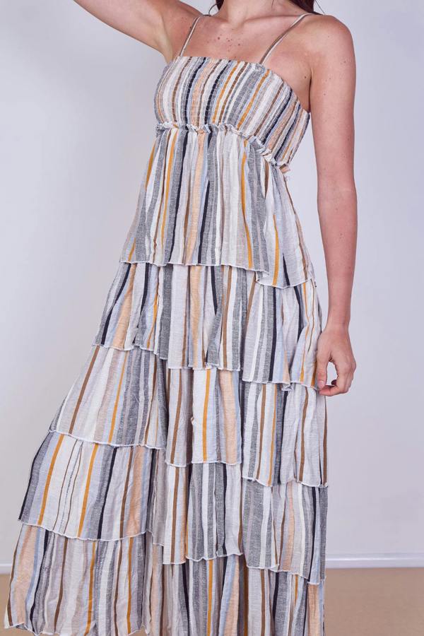 Woman wearing a tiered striped dress against a plain background