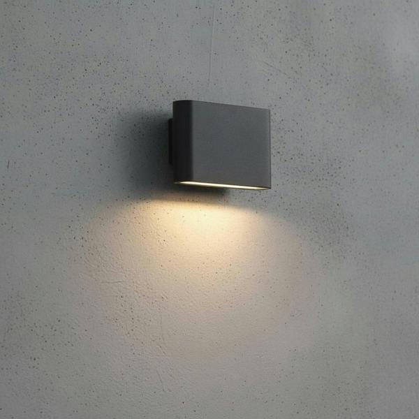 Black outdoor LED wall downlight mounted on a grey concrete exterior wall 