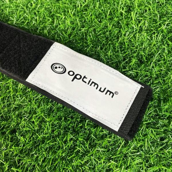 Close-up of black Optimum tag rugby belt velcro fastener with black logo on white panel, on grass