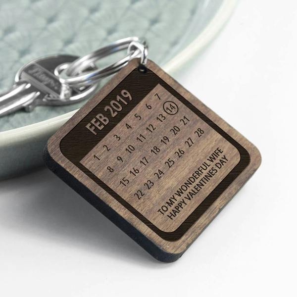 Personalised FSC walnut wood calendar keyring featuring the month of February 2019 with the 14th circled and the engraved text "To My Wonderful Wife, Happy Valentine's Day" lying on a textured blue plate.