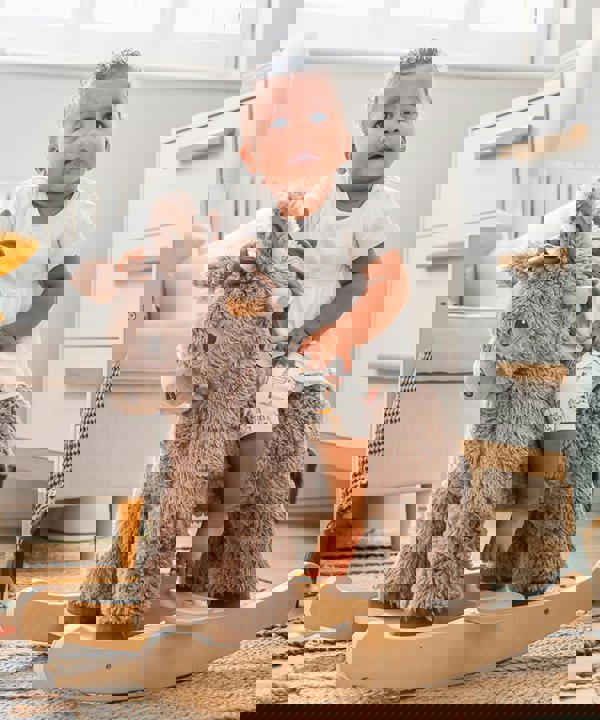 little girl rocking donkey ride on toy in nursery room 