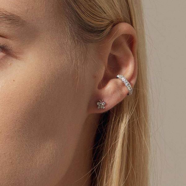 Close-up of a person wearing silver earrings with a neutral background. Small sterling silver butterfly studs by BLOOMTINE with 8 total brilliant-cut lab moissanites. These 5mm dainty, tarnish-resistant earrings are an ethical luxury staple, exclusively available at Wolf & Badger and Rackhams, perfect for birthdays and graduations