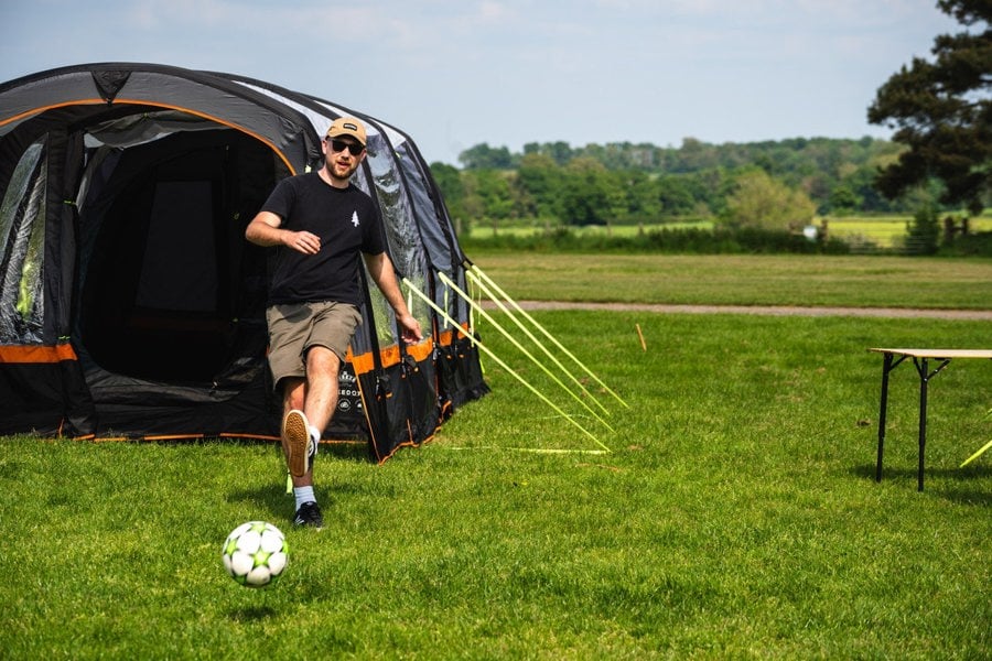 A male playing football outside of the OLPRO Blakedown Breeze® 4 Berth Inflatable Tent.