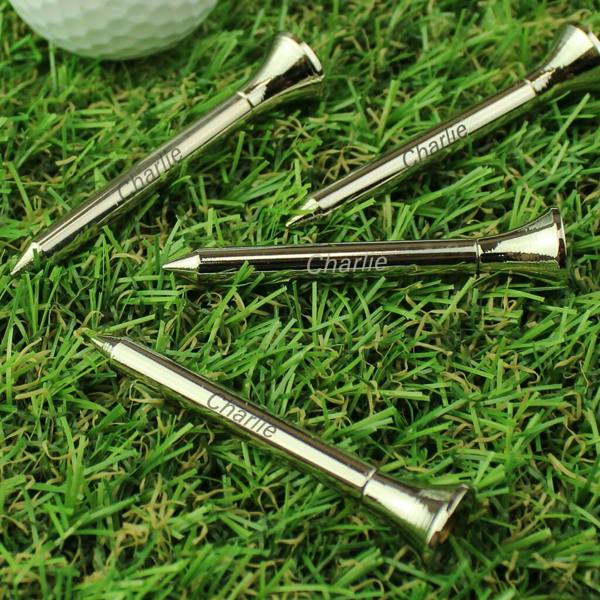 Personalised silver-plated golf tees engraved with the name "Charlie" displayed on a realistic grass surface with a golf ball in the background.