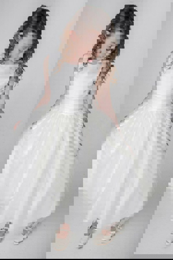 Young girl wearing an ivory dress on a plain background