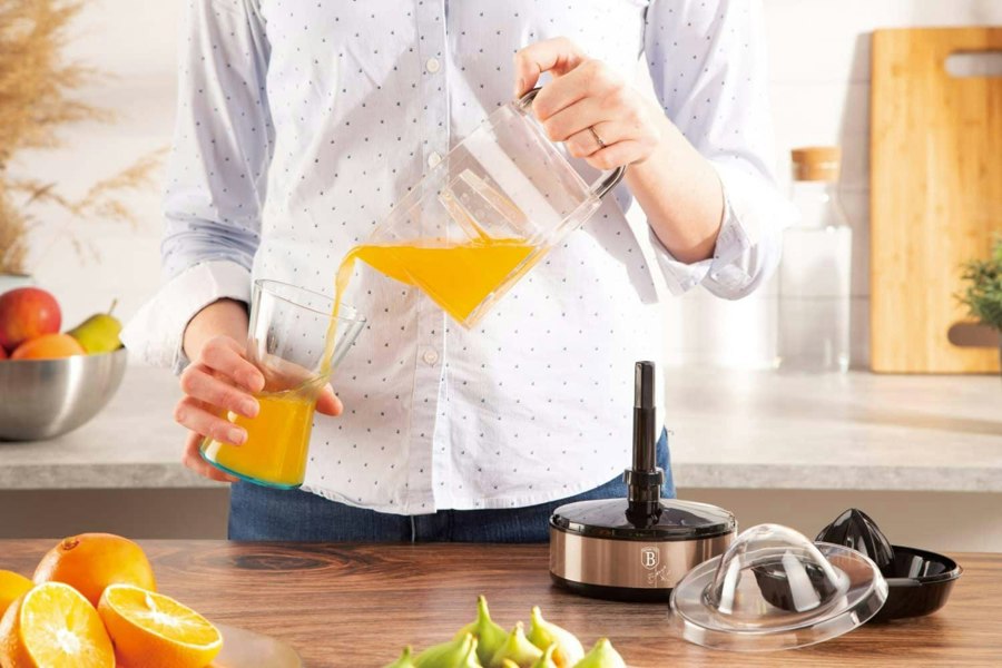 Woman pouring freshly squeezed juice from the Berlinger Haus BH/9385 Electric Citrus Juicer into a cup.