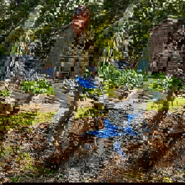 7.5hp petrol rotavator in action, featuring a blue body, sturdy wheels, and a powerful engine, tilling rich soil in a garden setting