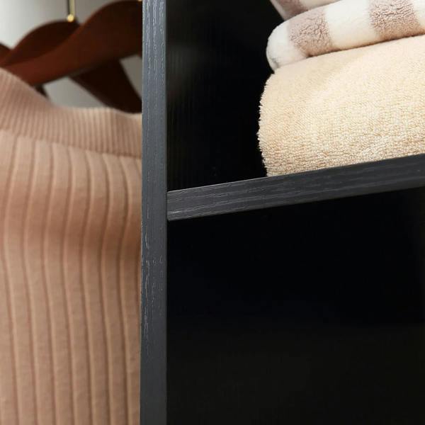 Black open wardrobe shelf with stacked towels in a storage compartment