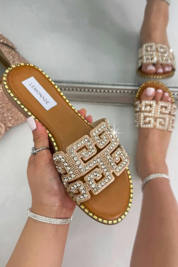 Pink embellished sandals being held in hand